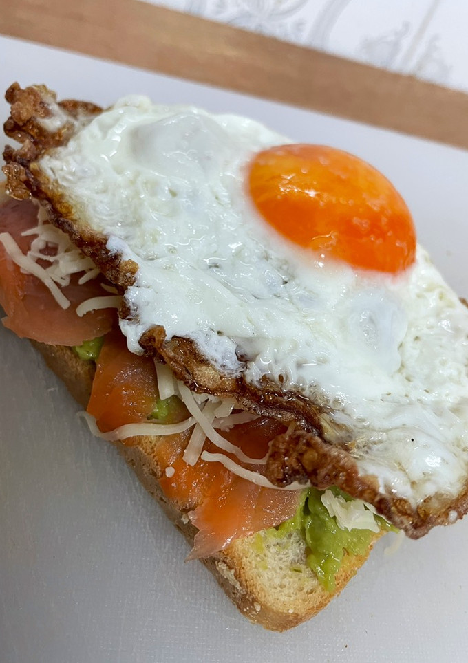 Una foto de Tosta de guacamole, salmón ahumado y huevo frito