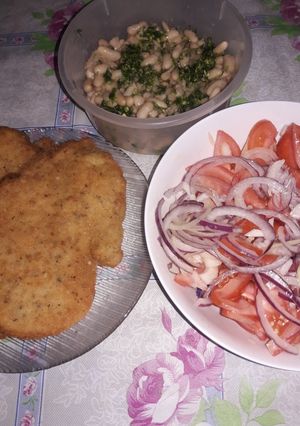 Una foto de Milanesas de pollo, porotos, tomates, cebolla