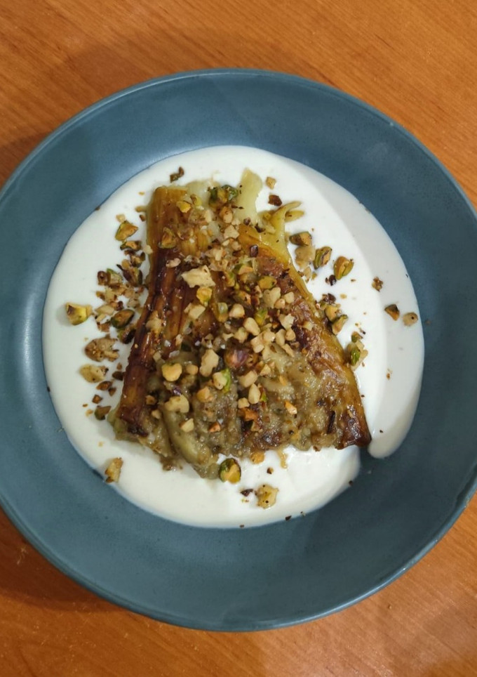 Una foto de Berenjena asada con salsa de ricotta y pistachos