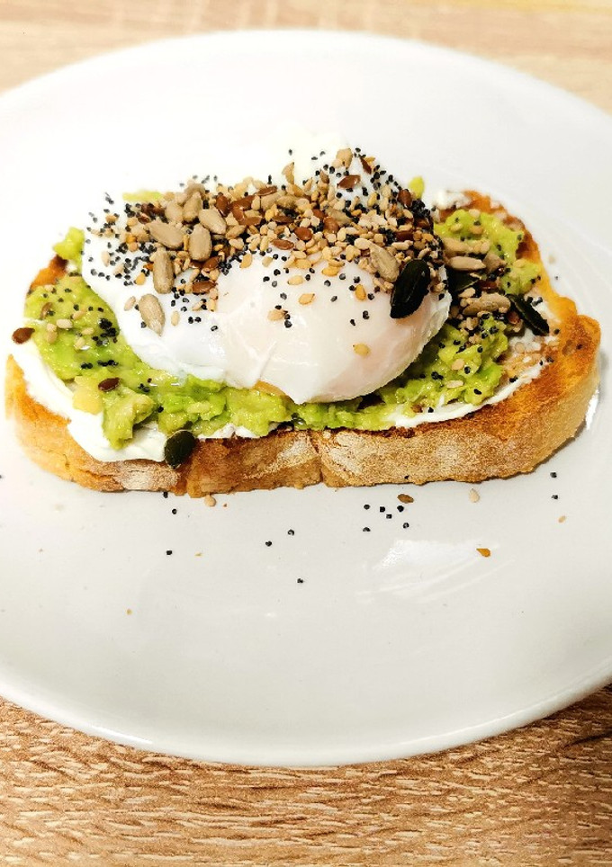 Una foto de Tosta de aguacate, queso crema, semillas y huevo poché
