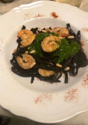 A picture of Squid Ink Tagliolini with Grilled Shrimp, Mustard Pesto, and Toasted Pine Nuts.