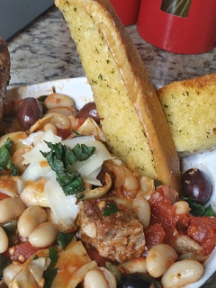 A picture of Grilled Sausage and Cannellini Beans Puttanesca w/ Garlic Bread.