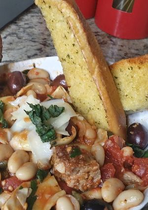 A picture of Grilled Sausage and Cannellini Beans Puttanesca w/ Garlic Bread.
