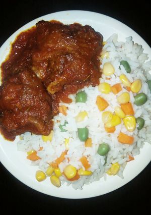 A picture of Boiled rice with vegetables,tomato sauce and chicken.