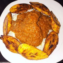 A picture of Groundnut stew with rice and plantains.