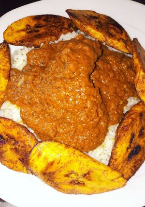 A picture of Groundnut stew with rice and plantains.