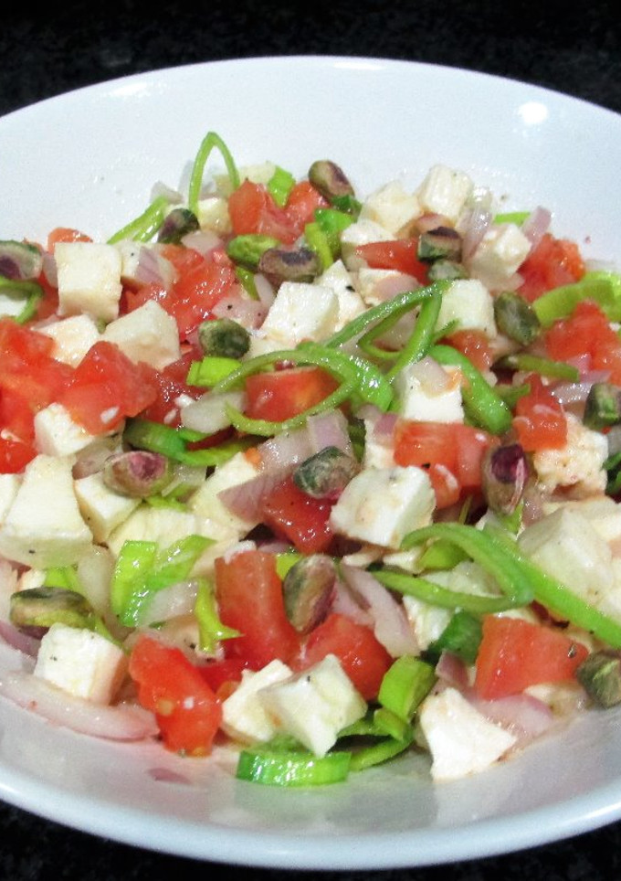 Una foto de Ensalada de mozzarella con tomate, cebolla y pistachos