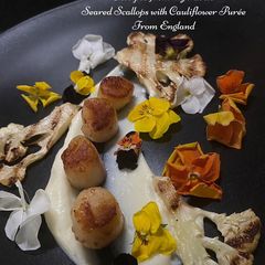 A picture of Seared scallops with cauliflower puree, chargrilled cauliflower and edible flowers.