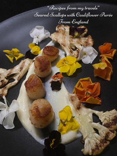 A picture of Seared scallops with cauliflower puree, chargrilled cauliflower and edible flowers.