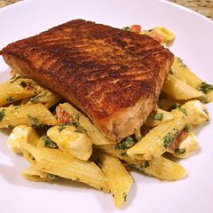 A picture of Blackened salmon over smokey mozzarella pasta.