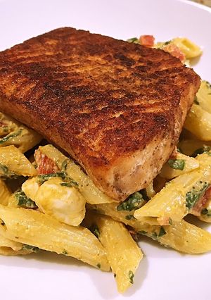 A picture of Blackened salmon over smokey mozzarella pasta.