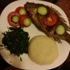 A picture of Deep fried whole served with Ugali and spinach.