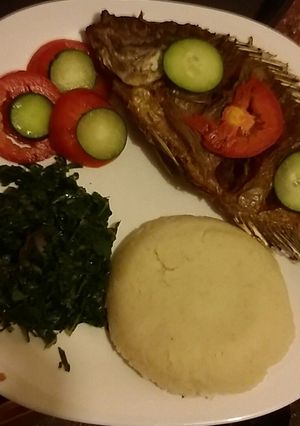 A picture of Deep fried whole served with Ugali and spinach.