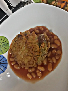 A picture of Annie's Noodles croquettes embedded in baked beans.