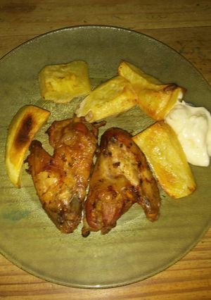 Una foto de Alitas de pollo con papas al horno😋😋😋😋