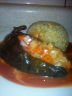 Una foto de Chile poblano relleno de ensalada de verduras acompañado de arroz bañado con salsa de tomate