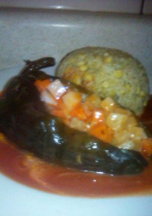 Una foto de Chile poblano relleno de ensalada de verduras acompañado de arroz bañado con salsa de tomate