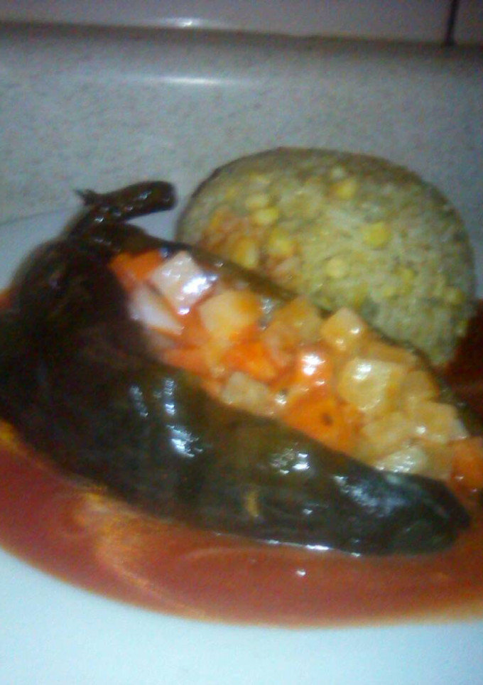 Una foto de Chile poblano relleno de ensalada de verduras acompañado de arroz bañado con salsa de tomate