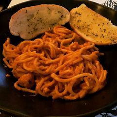 A picture of Tomato noodles with garlic bread.