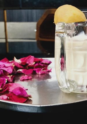 A picture of Chikoo shake with rose petals.
