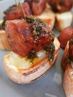 Una foto de Choripan en pincho con provolone y chimichurri