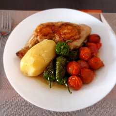 Una foto de Pollo hervido con guarnición de pimientos del padrón y tomatitos