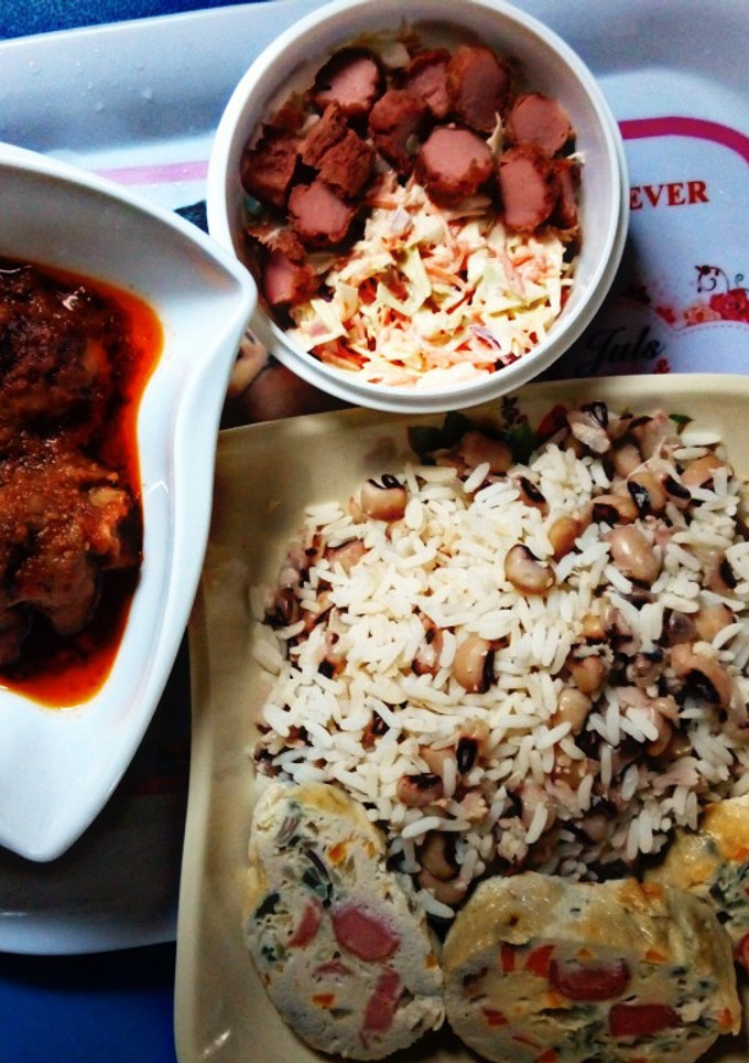 A picture of Rice and beans with stew and coleslaw with boiled egg.