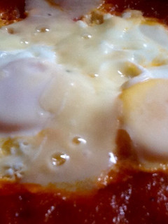 Una foto de Huevos escalfados en salsa de tomate y lascas de parmesano