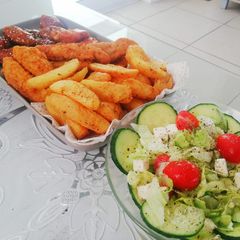 Fried chicken strips, potato wedges and a light green salad A picture of Fried chicken strips, potato wedges and a light green salad.