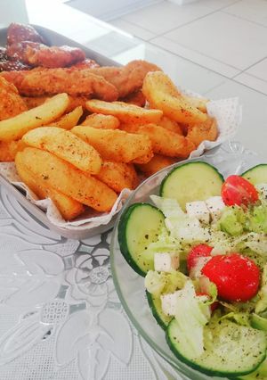 A picture of Fried chicken strips, potato wedges and a light green salad.