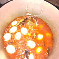 A picture of Tomato stew with smoked fish and eggs.