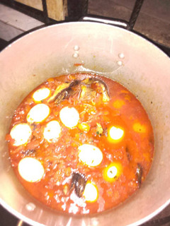A picture of Tomato stew with smoked fish and eggs.