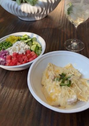 A picture of Four Cheese Ravioli with Alfredo Sauce and Grecian Salad.