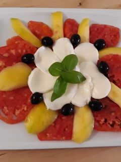 Una foto de Carpaccio de tomate con mozzarella y mango
