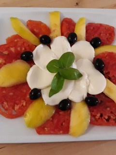 Una foto de Carpaccio de tomate con mozzarella y mango