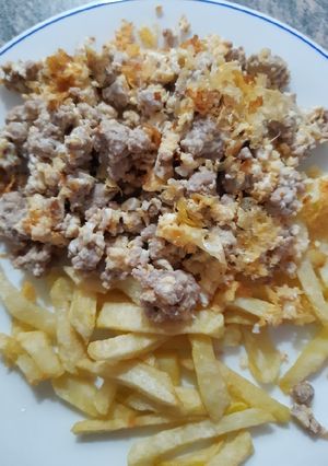 Una foto de Carne picada con huevos rotos y patatas fritas