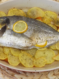 Una foto de Dorada al horno sobre lecho de patatas, cebolla y pimiento