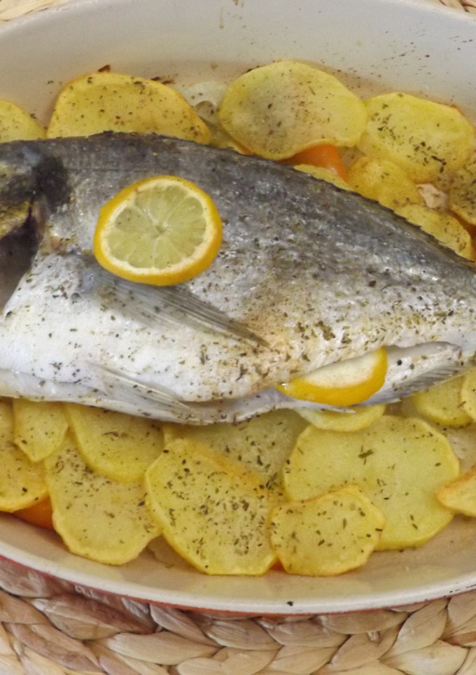 Una foto de Dorada al horno sobre lecho de patatas, cebolla y pimiento