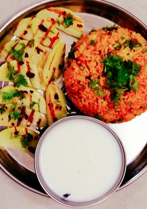 A picture of Red fried rice and potato weges.