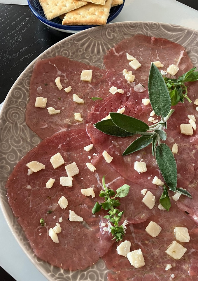 Una foto de Carpaccio de vacuno con salsita de limón y parmesano