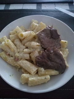 Una foto de Penne Riggati con salsa blanca acompañado con bistec
