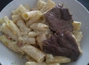 Una foto de Penne Riggati con salsa blanca acompañado con bistec