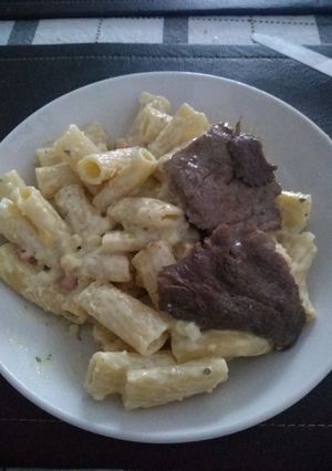 Una foto de Penne Riggati con salsa blanca acompañado con bistec