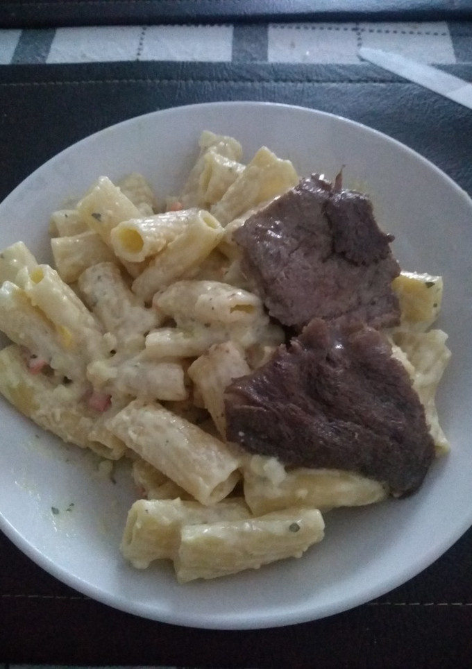 Una foto de Penne Riggati con salsa blanca acompañado con bistec