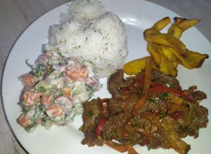 Una foto de Carne de res salteada acompañada de ensalada rusa