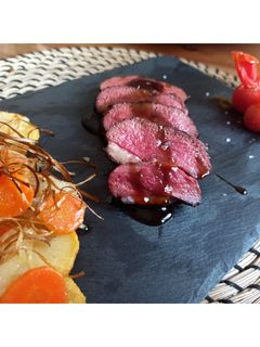 Una foto de Magret de pato con salsa de naranja y guarnición