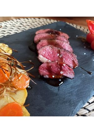 Una foto de Magret de pato con salsa de naranja y guarnición