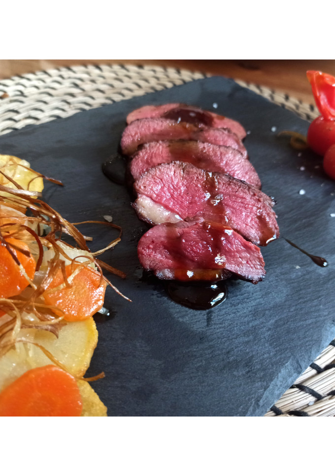 Una foto de Magret de pato con salsa de naranja y guarnición