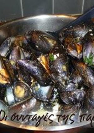 A picture of Steamed mussels with various herbs.