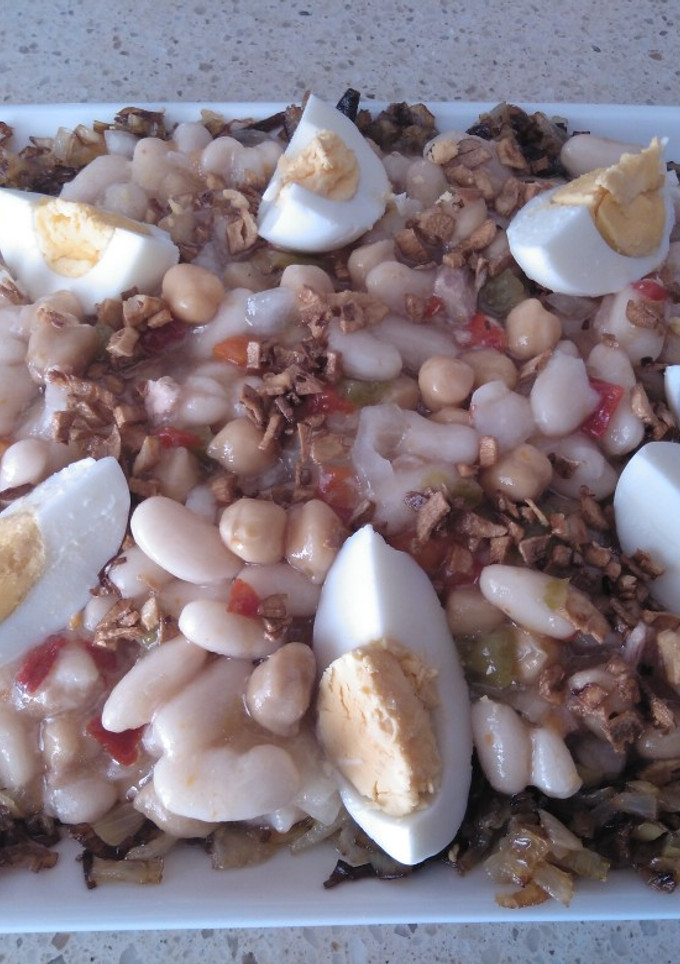 Una foto de Ensalada templada de legumbres en cama de cebolla y puerro